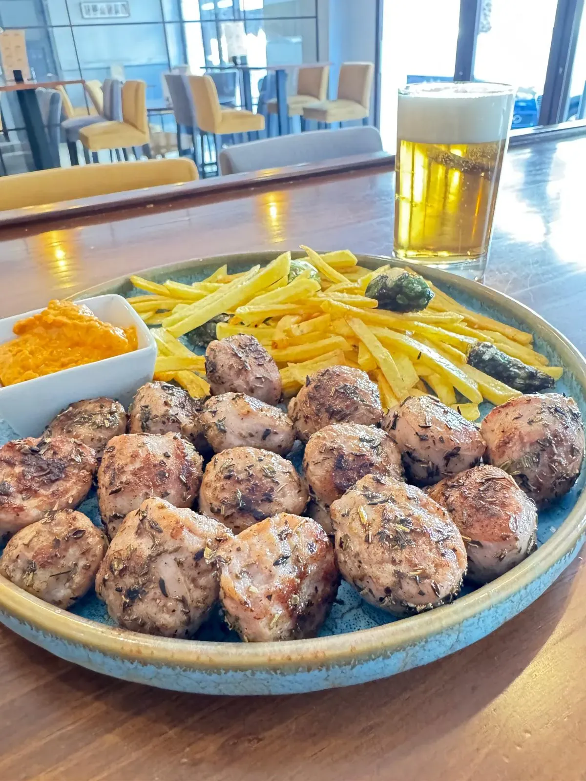 Butifarra con patatas paja, pimientos y romesco, junto a una caña