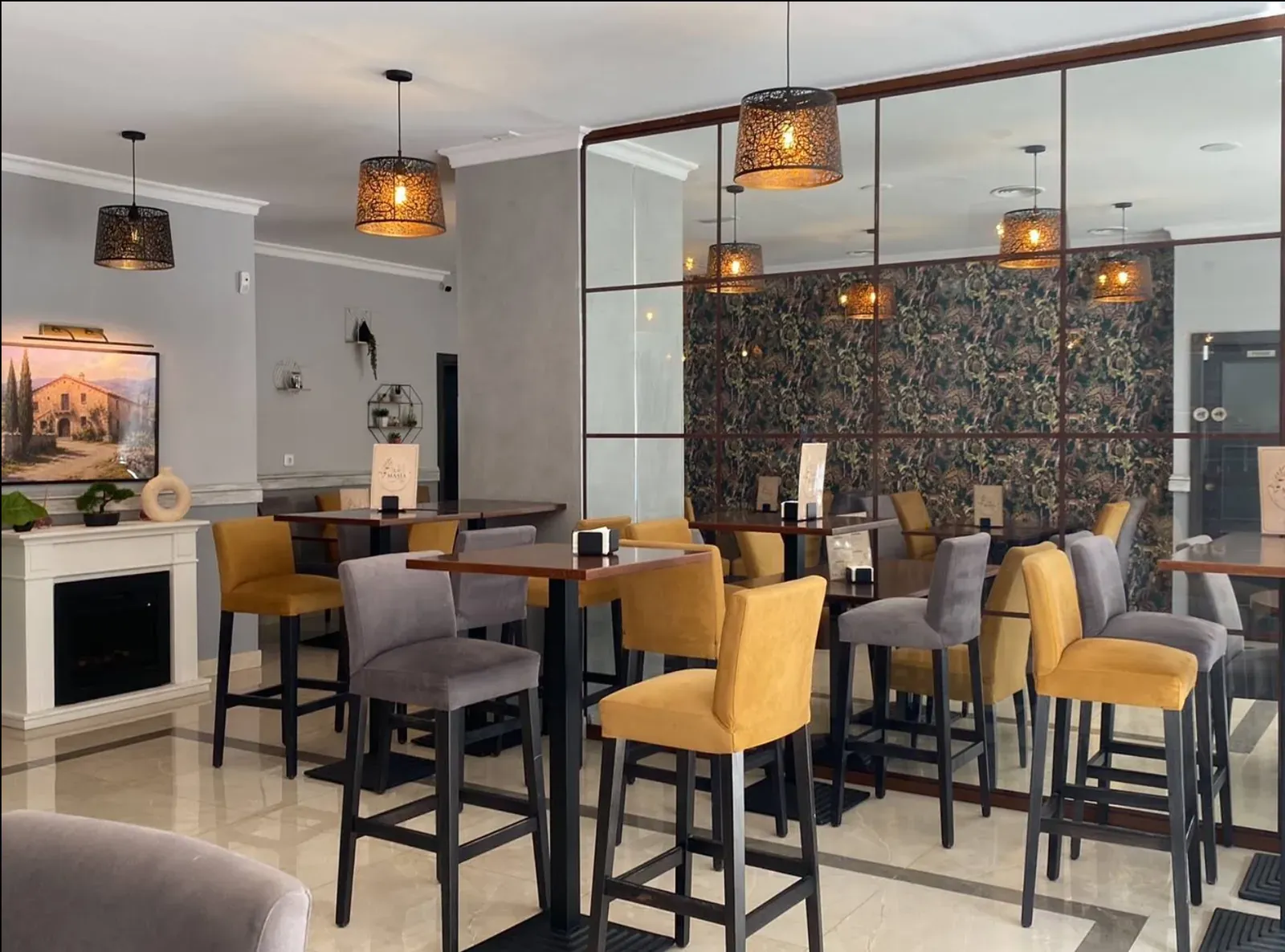 Salón de Bar La Masía con lámparas de filigrana encendidas y taburetes de terciopelo mostaza